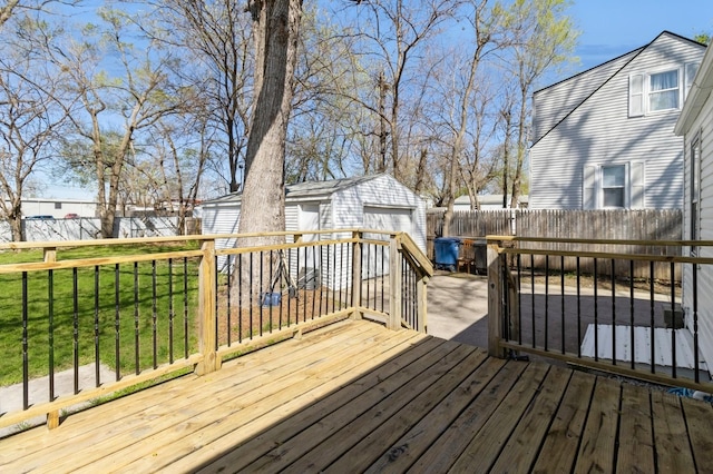 wooden terrace with an outbuilding, a detached garage, fence, and a yard