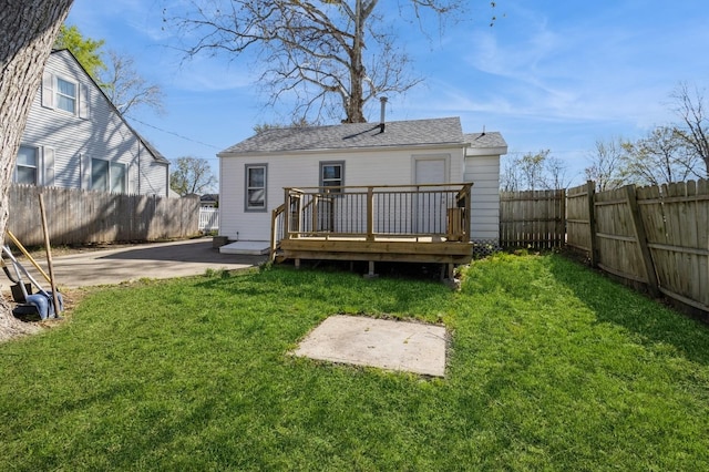 back of property with a yard, a fenced backyard, a patio, a wooden deck, and roof with shingles