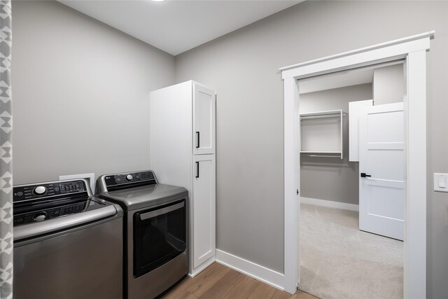 5009 148th Cir, Urbandale, IA 50323 - washroom with separate washer and dryer, cabinet space, baseboards, and light wood-style floors