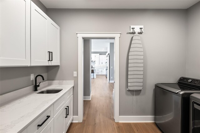 5009 148th Cir, Urbandale, IA 50323 - laundry room with cabinet space, separate washer and dryer, light wood-type flooring, and baseboards