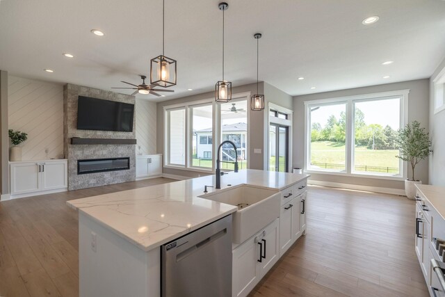 5009 148th Cir, Urbandale, IA 50323 - kitchen with stainless steel dishwasher, a ceiling fan, open floor plan, a sink, and light wood-style flooring
