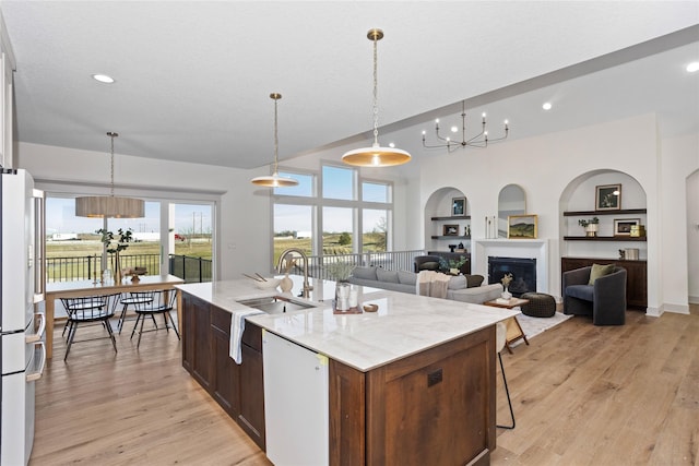 5027 NE Seneca Dr, Ankeny, IA 50021 - kitchen featuring white appliances, a chandelier, built in features, a sink, and a center island with sink