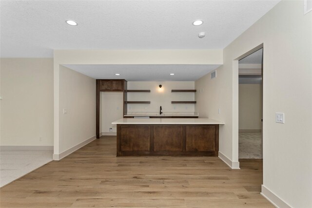 5027 NE Seneca Dr, Ankeny, IA 50021 - kitchen featuring a peninsula, light countertops, light wood finished floors, open shelves, and baseboards
