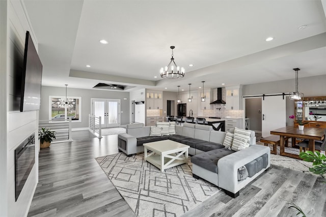 875 Roman Rd, Waukee, IA 50263 - living area featuring a chandelier, a barn door, light wood-style floors, recessed lighting, and a tray ceiling