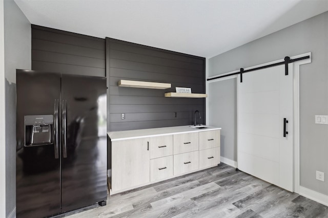 875 Roman Rd, Waukee, IA 50263 - kitchen featuring black fridge, a barn door, light countertops, a sink, and light wood-type flooring