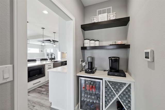 875 Roman Rd, Waukee, IA 50263 - bar area with black microwave, a sink, beverage cooler, and wood finished floors