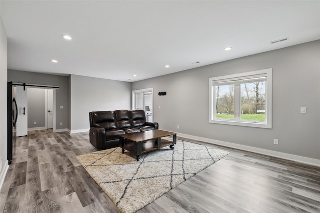 875 Roman Rd, Waukee, IA 50263 - living room featuring a barn door, wood finished floors, baseboards, and recessed lighting