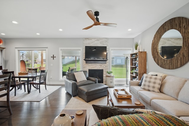 8704 Highland Oaks Dr, Johnston, IA 50131 - living room featuring a ceiling fan, dark wood-style floors, recessed lighting, a stone fireplace, and baseboards