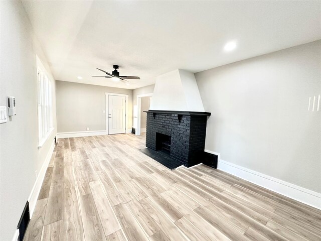 unfurnished living room with baseboards, a brick fireplace, a ceiling fan, recessed lighting, and light wood finished floors