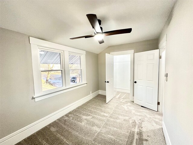 unfurnished bedroom featuring a closet, baseboards, carpet flooring, a ceiling fan, and lofted ceiling
