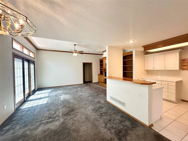 5925 Ep True Pkwy Unit 22, West Des Moines, IA 50266 - kitchen with white cabinets, a textured ceiling, visible vents, baseboards, and light carpet