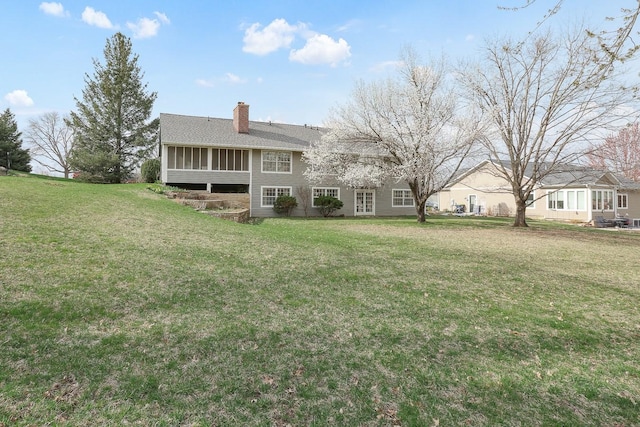 1113 Bruce Ln, Pella, IA 50219 - back of house with a sunroom, a chimney, and a lawn