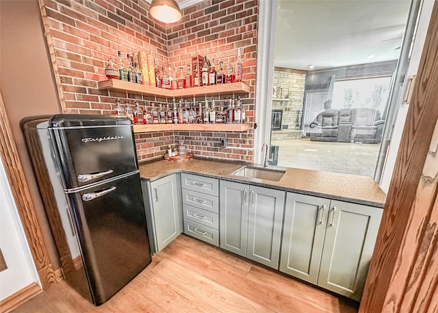 1009 198th Pl, Pella, IA 50219 - indoor wet bar featuring freestanding refrigerator, light wood-style flooring, ornamental molding, and brick wall