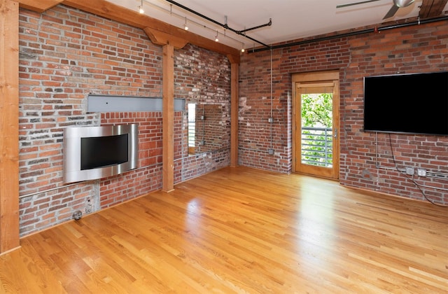 301 E Court Ave Unit 203, Des Moines, IA 50309 - unfurnished living room featuring wood finished floors, rail lighting, and brick wall