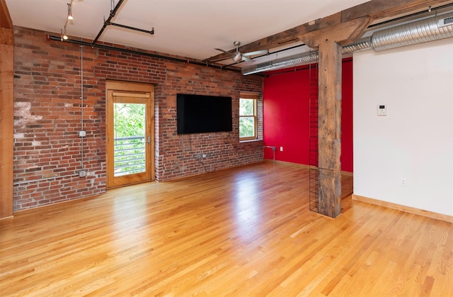 301 E Court Ave Unit 203, Des Moines, IA 50309 - unfurnished living room featuring rail lighting, wood finished floors, and brick wall