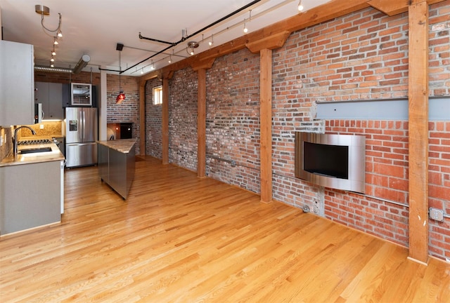 301 E Court Ave Unit 203, Des Moines, IA 50309 - kitchen featuring stainless steel fridge with ice dispenser, a fireplace, light wood-style flooring, brick wall, and light countertops