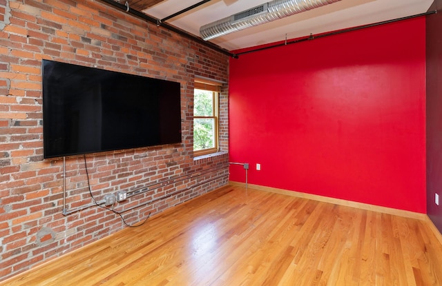 301 E Court Ave Unit 203, Des Moines, IA 50309 - unfurnished room with wood finished floors and brick wall