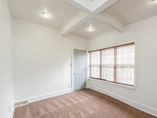 carpeted empty room featuring beamed ceiling, baseboards, and visible vents