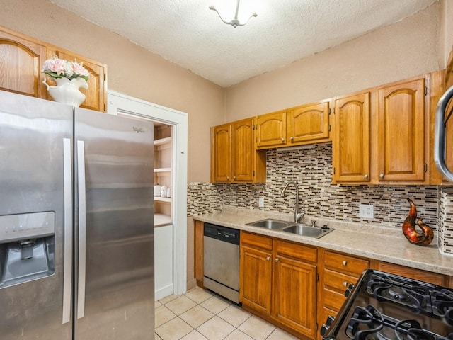 kitchen with stainless steel appliances, a sink, a textured ceiling, light tile patterned flooring, and backsplash