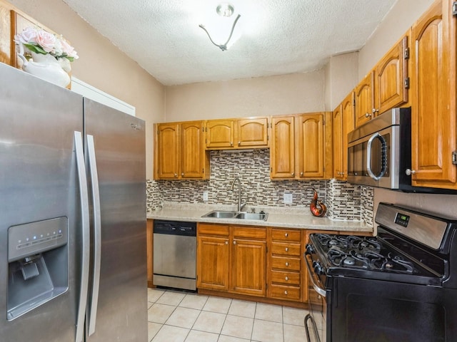 kitchen featuring light countertops, a textured ceiling, a sink, and stainless steel appliances