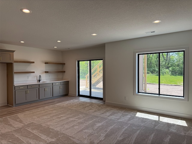 1112 2nd St NE, Altoona, IA 50009 - unfurnished living room with bar with sink, recessed lighting, a textured ceiling, baseboards, and carpet flooring