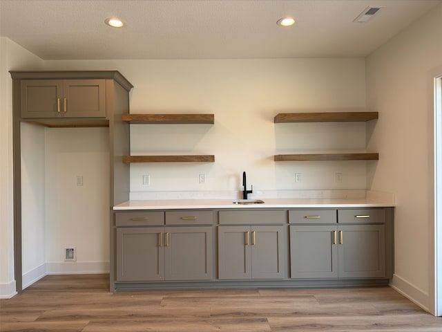 1112 2nd St NE, Altoona, IA 50009 - kitchen featuring open shelves, a sink, gray cabinetry, light wood-type flooring, and baseboards