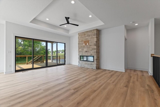 1112 2nd St NE, Altoona, IA 50009 - unfurnished living room featuring a raised ceiling, a ceiling fan, light wood-style floors, recessed lighting, and a fireplace