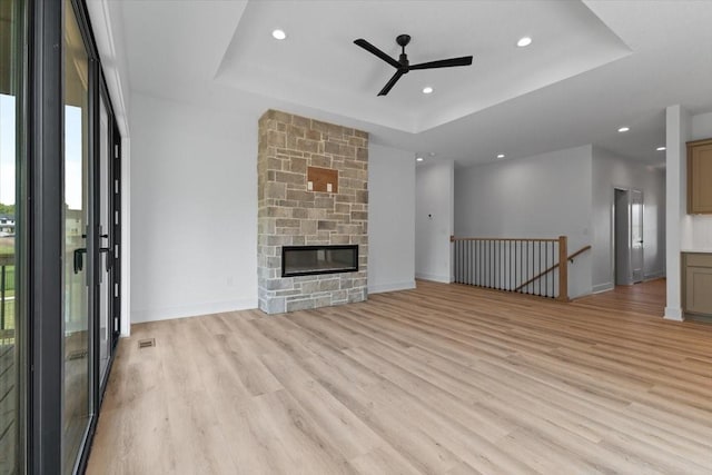 1112 2nd St NE, Altoona, IA 50009 - unfurnished living room with a tray ceiling, light wood-type flooring, a ceiling fan, recessed lighting, and baseboards