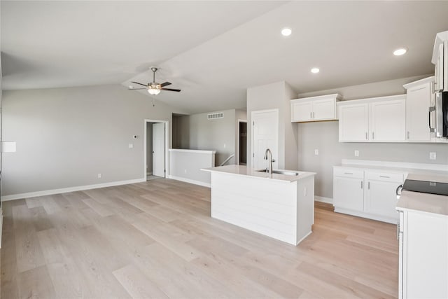 4413 NW Olivia Ln, Ankeny, IA 50023 - kitchen featuring a ceiling fan, an island with sink, white cabinetry, stainless steel microwave, and lofted ceiling