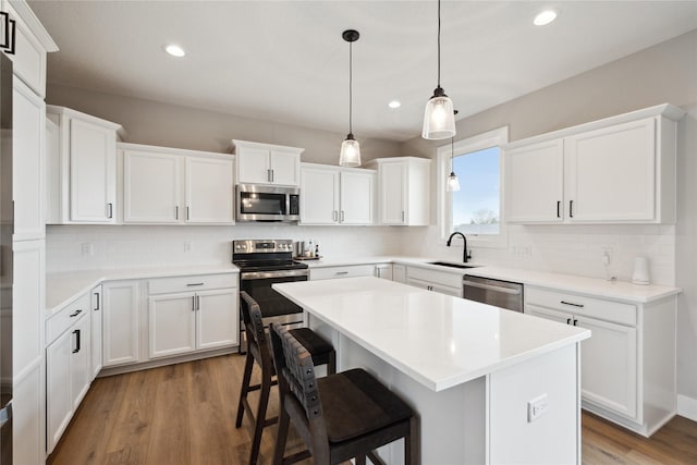 70 NW Hidden Knl, Waukee, IA 50263 - kitchen featuring stainless steel appliances, a sink, recessed lighting, wood finished floors, and tasteful backsplash