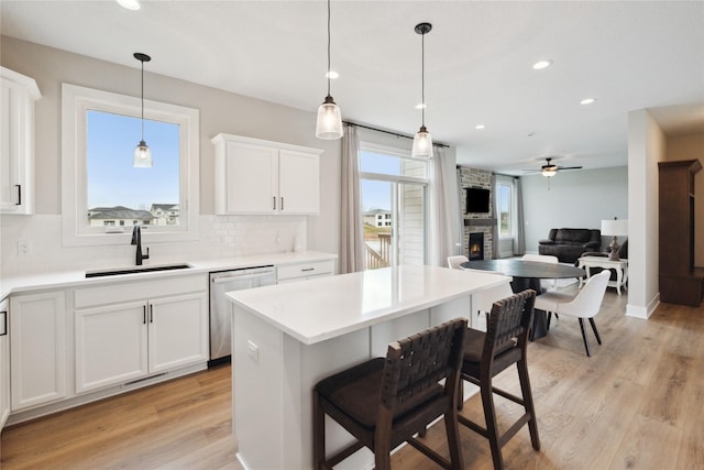 70 NW Hidden Knl, Waukee, IA 50263 - kitchen with stainless steel dishwasher, a sink, a fireplace, tasteful backsplash, and white cabinets