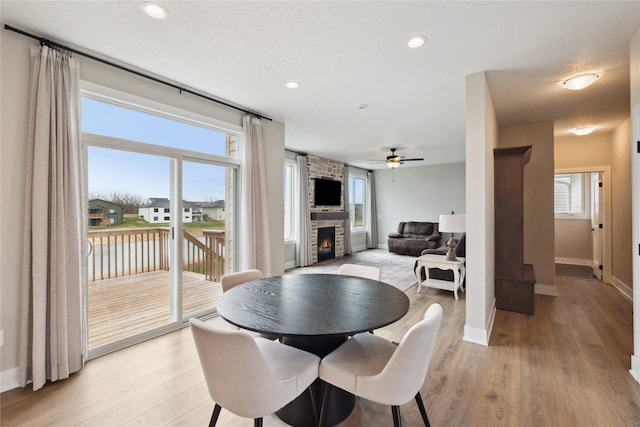 70 NW Hidden Knl, Waukee, IA 50263 - dining space with a stone fireplace, ceiling fan, light wood-style flooring, plenty of natural light, and recessed lighting