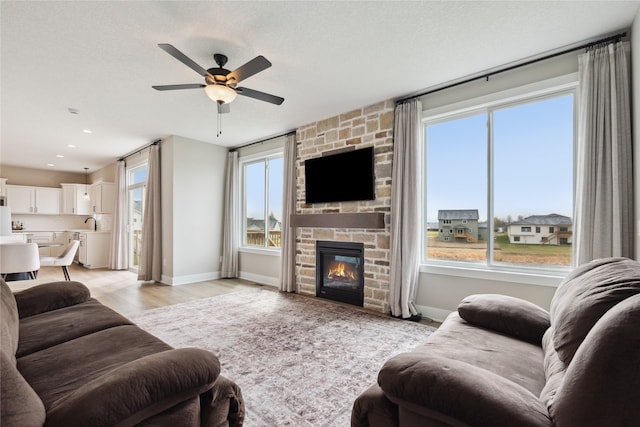 70 NW Hidden Knl, Waukee, IA 50263 - living room with ceiling fan, baseboards, light wood-style flooring, a stone fireplace, and recessed lighting