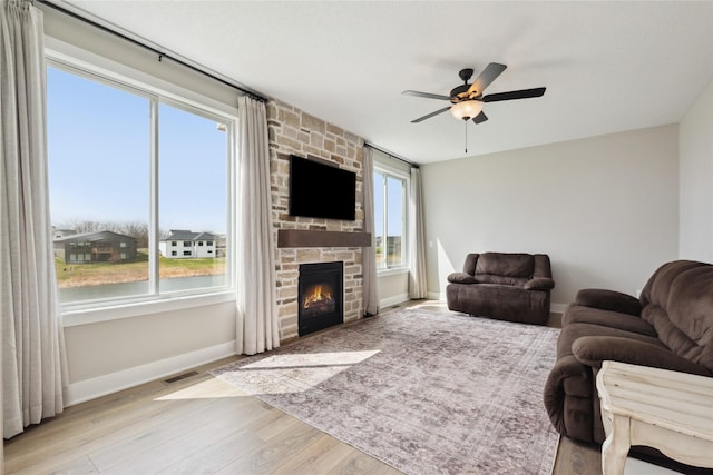 70 NW Hidden Knl, Waukee, IA 50263 - living room featuring a ceiling fan, wood finished floors, a stone fireplace, and baseboards