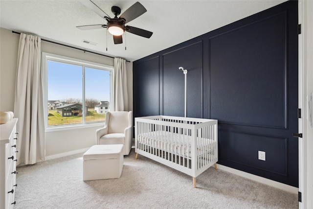 70 NW Hidden Knl, Waukee, IA 50263 - carpeted bedroom with a crib, multiple windows, baseboards, and ceiling fan