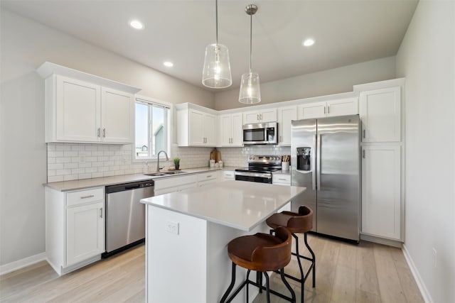 1715 Willow Ct, Norwalk, IA 50211 - kitchen featuring light wood finished floors, a center island, a sink, decorative backsplash, and appliances with stainless steel finishes