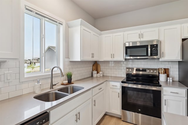 1715 Willow Ct, Norwalk, IA 50211 - kitchen featuring white cabinets, a sink, decorative backsplash, light countertops, and appliances with stainless steel finishes