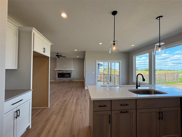 1910 Silver Maple Dr, Norwalk, IA 50211 - kitchen with a sink, a stone fireplace, recessed lighting, light wood finished floors, and a ceiling fan
