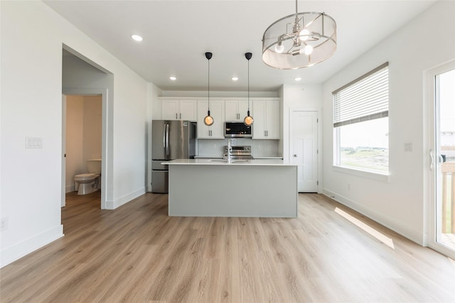 4125 NE 6th St, Ankeny, IA 50021 - kitchen featuring appliances with stainless steel finishes, white cabinets, light countertops, an island with sink, and tasteful backsplash