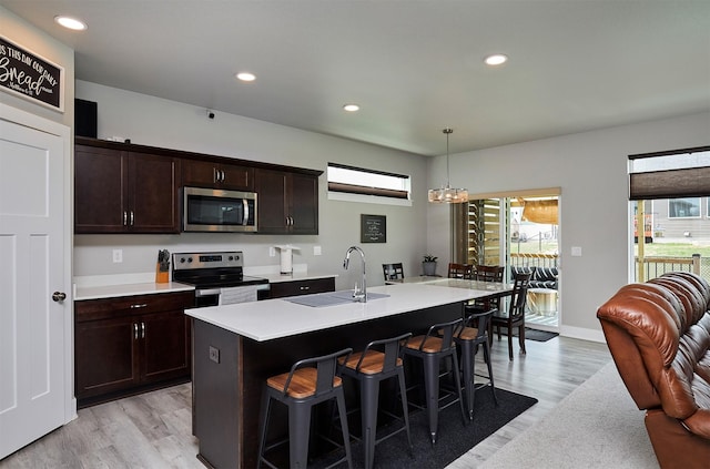 kitchen with stainless steel appliances, light wood-style floors, a kitchen breakfast bar, and light countertops