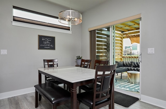 dining area with wood finished floors, an inviting chandelier, and baseboards