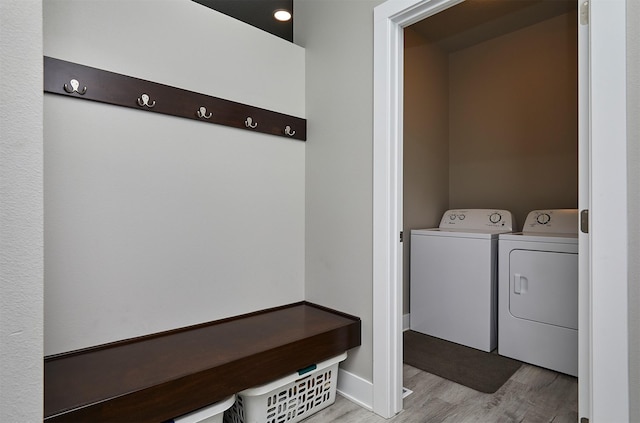 clothes washing area featuring light wood-type flooring, separate washer and dryer, and laundry area