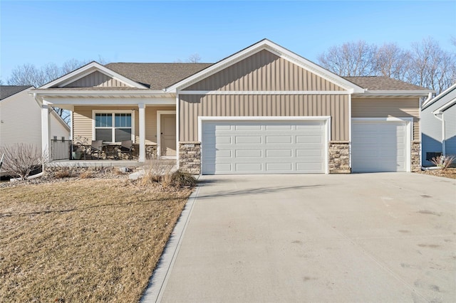 craftsman inspired home with board and batten siding, a garage, covered porch, stone siding, and driveway