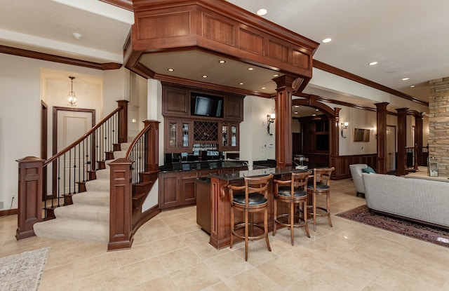 7580 NW 100th St, Johnston, IA 50131 - indoor bar featuring decorative columns, ornamental molding, stairs, light tile patterned floors, and a wainscoted wall
