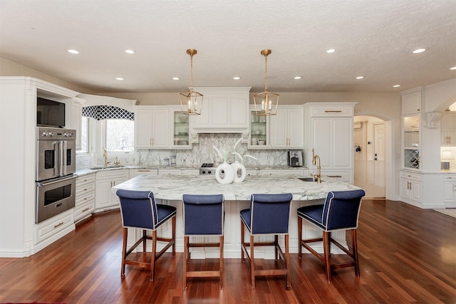 7580 NW 100th St, Johnston, IA 50131 - kitchen with stainless steel double oven, dark wood-style floors, backsplash, white cabinets, and recessed lighting