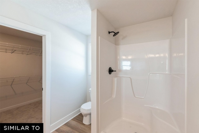 4201 NE 5th St, Ankeny, IA 50021 - full bathroom featuring walk in shower, baseboards, toilet, a walk in closet, and wood finished floors