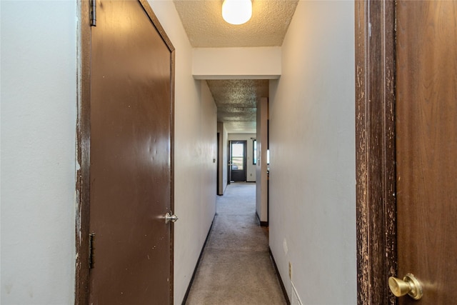 corridor featuring carpet flooring and a textured ceiling