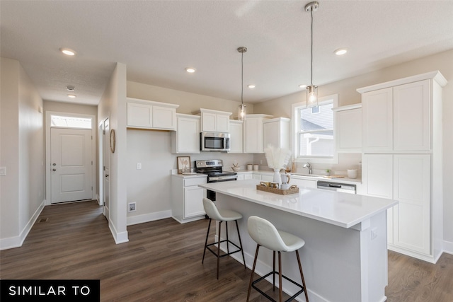 4215 NE 3rd St, Ankeny, IA 50021 - kitchen with dark wood-style floors, a center island, white cabinetry, and stainless steel appliances