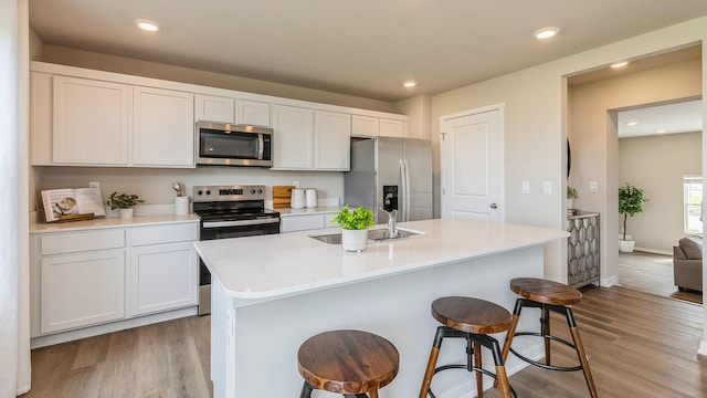 1048 34th St SE, Altoona, IA 50009 - kitchen with a sink, appliances with stainless steel finishes, a center island with sink, light wood-style flooring, and a breakfast bar area
