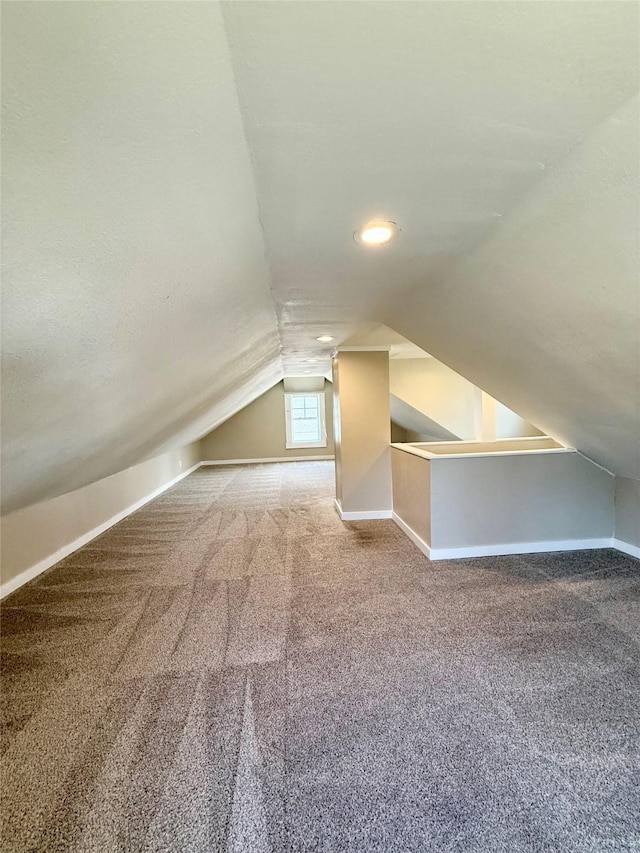 additional living space with baseboards, vaulted ceiling, and carpet flooring